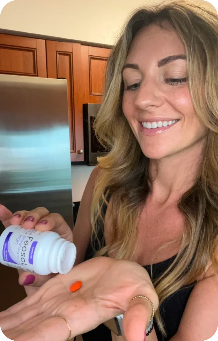 Smiling woman taking 1 capsule of Feosol